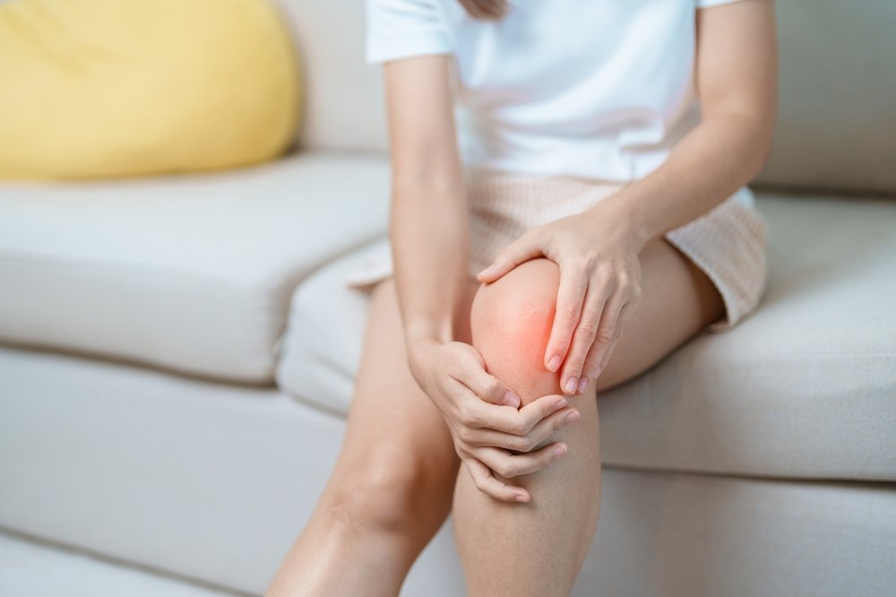 woman sitting on a couch holding her painful knee