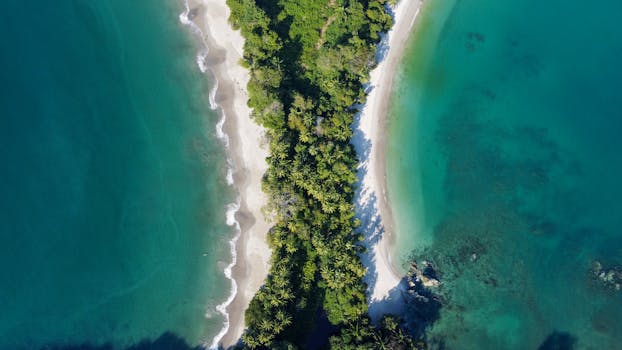Stunning aerial view of Manuel Antonio Beach with lush green forest and turquoise ocean waters in Costa Rica.