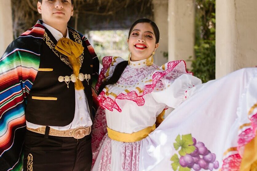 Mexican couple in traditional attire celebrating cultural heritage outdoors.