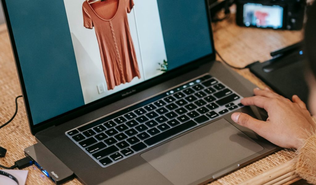 Professional photographer editing clothing images on a laptop with camera nearby.